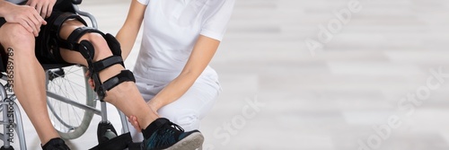 Physiotherapist Fixing Knee Braces On Man's Leg