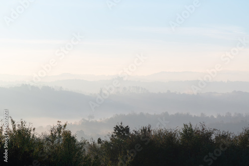 Hills with forest in fog at autumn morning, misty forest layers in autumn