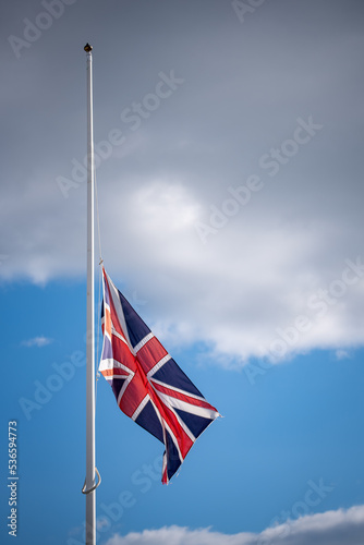 Union Jack flying at half mast with blue sky background.