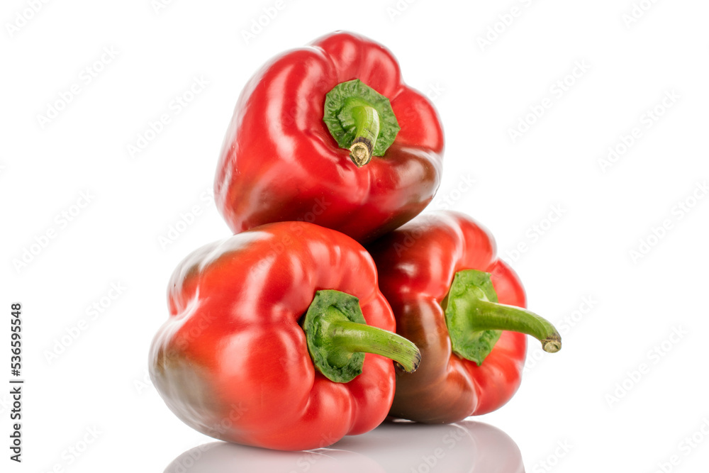 Three red organic, bell peppers, close-up, on a wooden table.