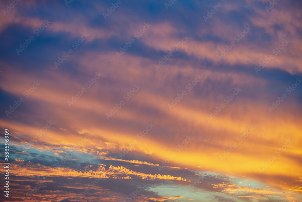 Dramatic colorful sunset. Fantasy landscape with clouds and orange sunset. Lines of clouds lighted by orange sundown sun