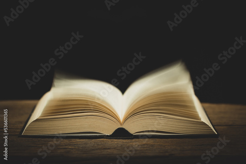 open bible on the antique wooden table in a dark room with light abstract style