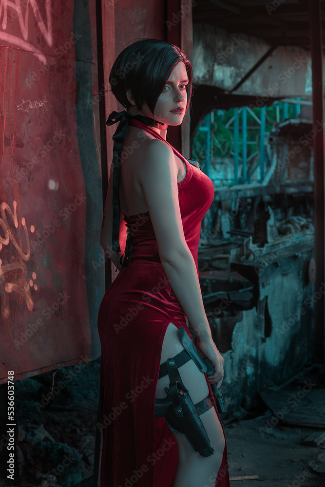 Naklejka premium young beautiful girl in an evening red dress with a gun