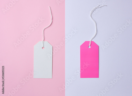 Empty white and pink cardboard tag on a white rope, pink background. Price tag template