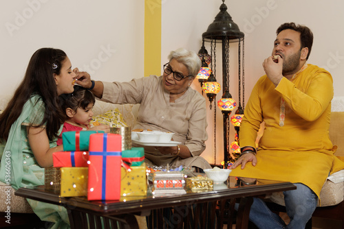 Young girl, kid, dressed up in ethnic wear siting along with grandmother and father, family celebrating diwali Hindu festival Laxmi poojan