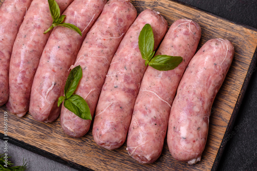 Raw sausages with ingredients on a cutting board on a dark concrete background with copy space Raw sausages with ingredients on a cutting board on a dark concrete background with copy space