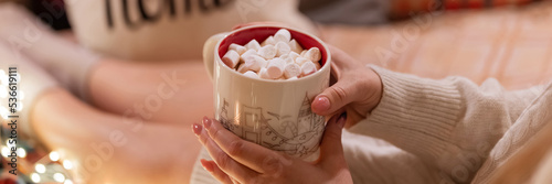 Murais de parede cup of hot chocolate or coffee drink with marshmallows in female holding hands of woman in knitted sweater relaxing and enjoyment the holidays in bed home on christmas or new year holidays eve