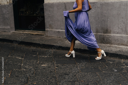 woman wearing an elegant dress crosses a street in Italy