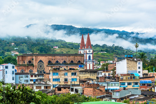 Landscape view of Moniquira, Boyaca, Colombia with a big church, buildings. Green mountains with fog and clouds in the background photo