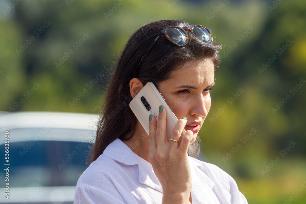 A young Portrait of young business woman with mobile phone outdoors is cutting her hair, an act of protest