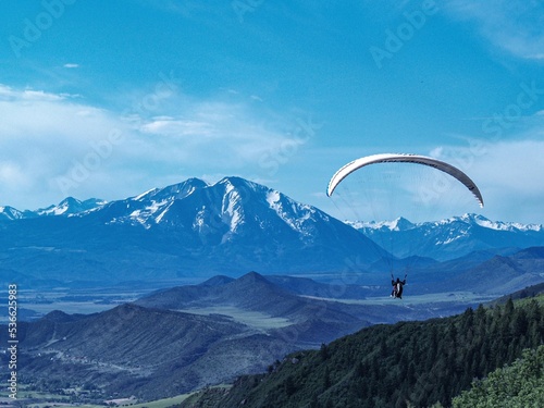 paraglider over Colorado mountains with snow caps in the background