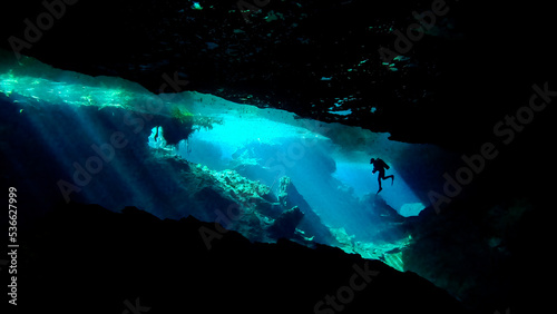 man scuba diving alone in chac mool cenote near cancun mexico seen from below