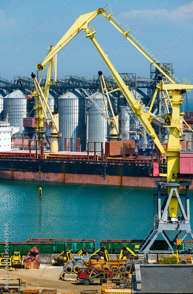 industrial seaport infrastructure, sea, cranes and dry cargo ship, grain silo, bulk carrier vessel and grain storage elevators, concept of sea cargo transportation industrial seaport infrastructure, sea, cranes and dry cargo ship, grain silo, bulk carrier vessel and grain storage elevators, concept of sea cargo transportation