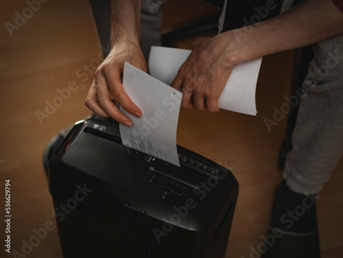 Fotografija Hands of a caucasian young man destroying documents in a paper cutting machine