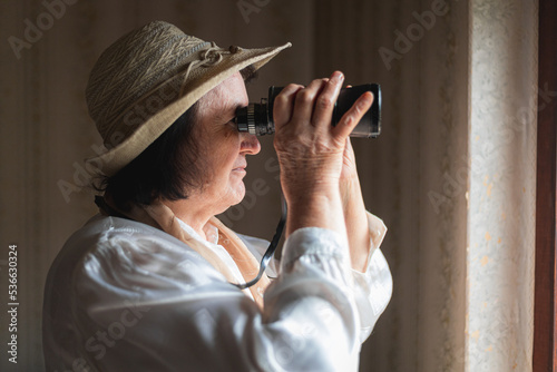 Fotografie Elderly woman looking through the binoculars, spying