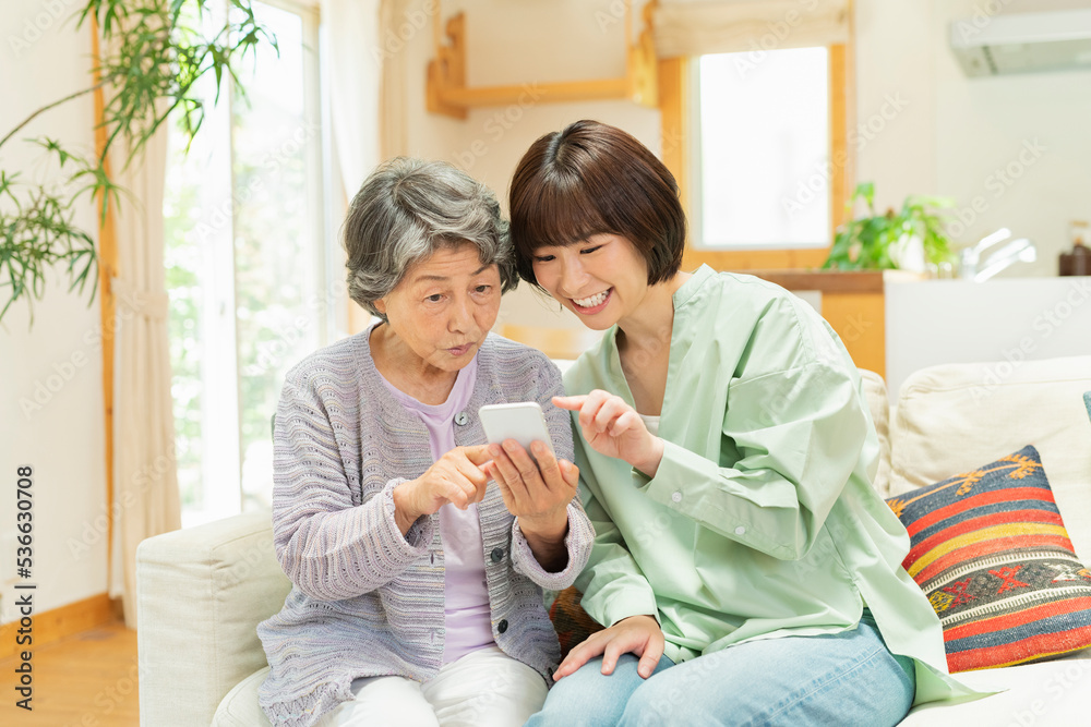 孫にスマートフォンの使い方を教わるシニア女性 孫にスマートフォンの使い方を教わるシニア女性