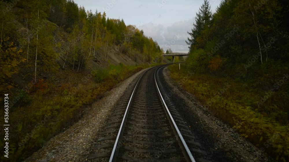 Aerial view of the railway and road bridge next to the hills covered beautiful gold autumn forest under clouds sky Aerial view of the railway and road bridge next to the hills covered beautiful gold autumn forest under clouds sky
