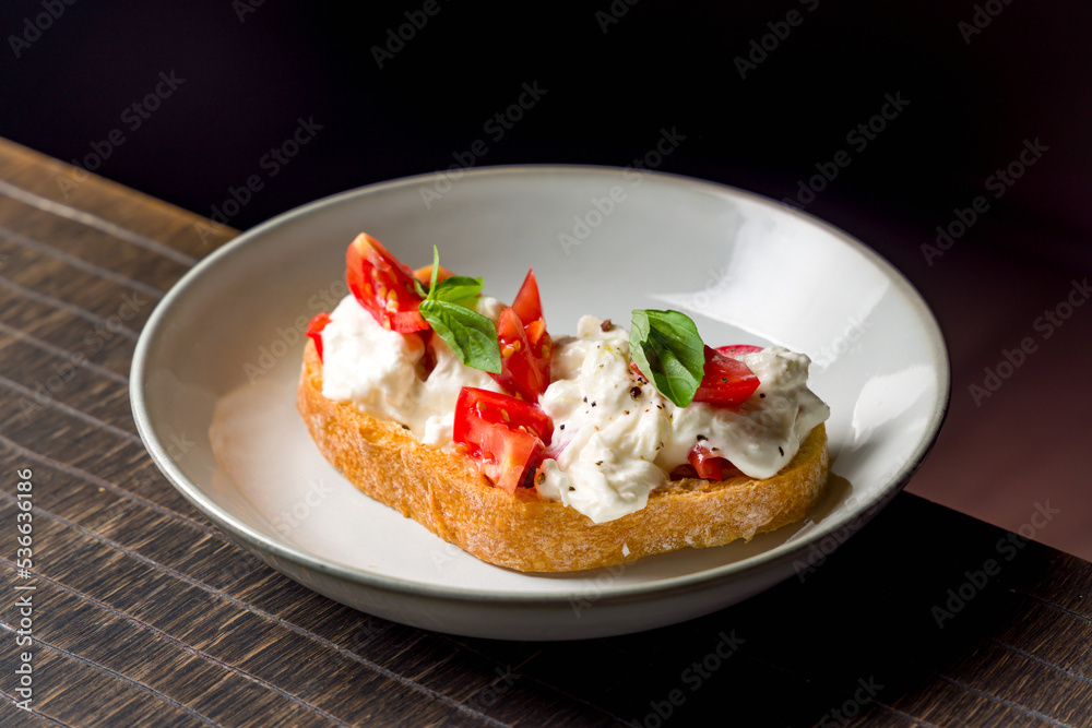 bruschetta with tomatoes and cheese strachatella on plate