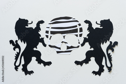 black and white skull head silhouette with two black heraldic lion shapes