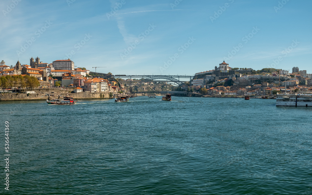 Panoramic view over the Douro River and traditional tourist transport boat's and the D. Luis I Bridge in the background. City of Porto in Portugal.