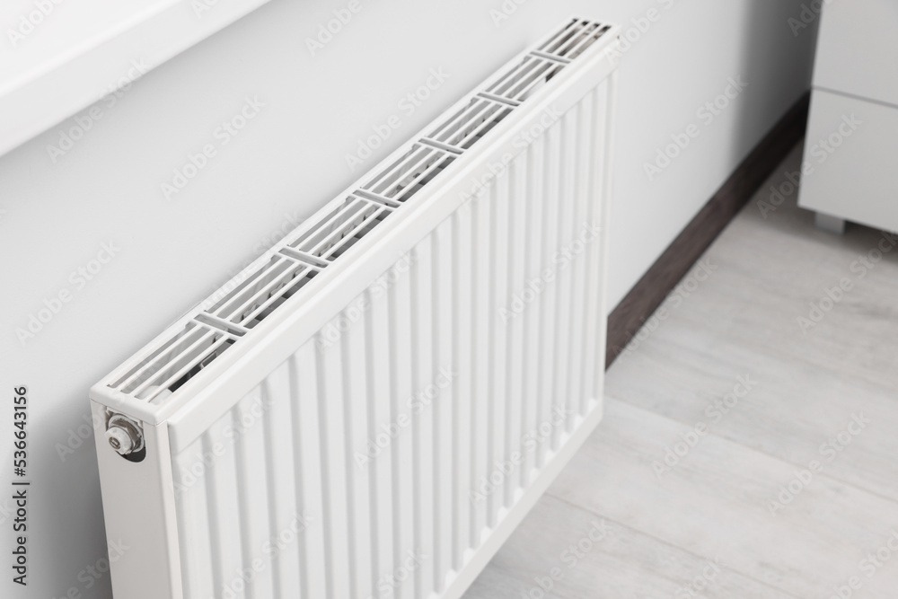 Modern radiator on white wall in room. Central heating system Modern radiator on white wall in room. Central heating system