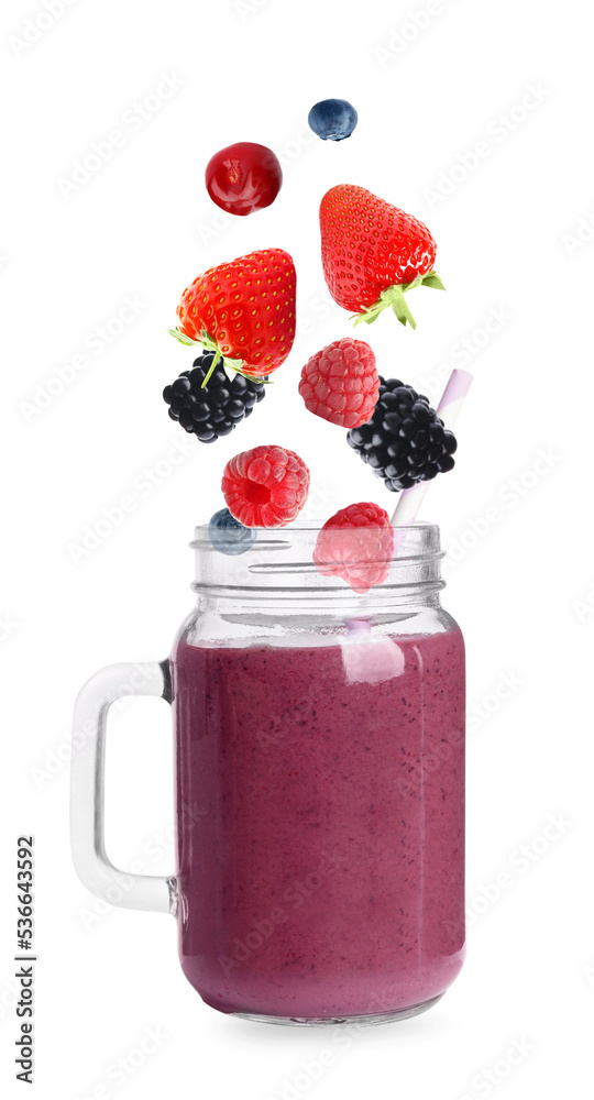 Fresh berries falling into glass with tasty smoothie on white background