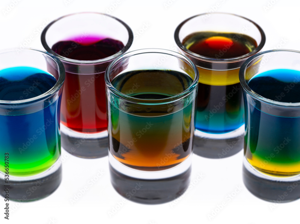 Colored water layers in shot glasses isolated on white background Colored water layers in shot glasses isolated on white background