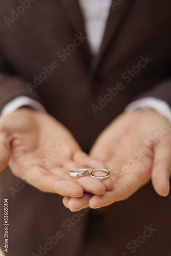 a man in suite is holding a pair of wedding ring 