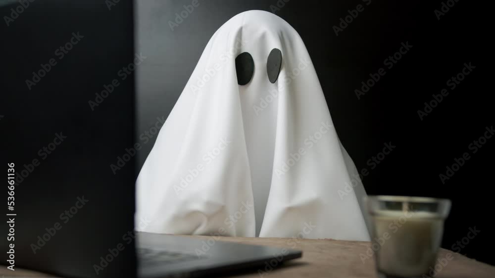 Ghost writing an article on laptop. Home office. Person working or studying in halloween. Ghostwriter typing on a computer. Ghost writing an article on laptop. Home office. Person working or studying in halloween. Ghostwriter typing on a computer.
