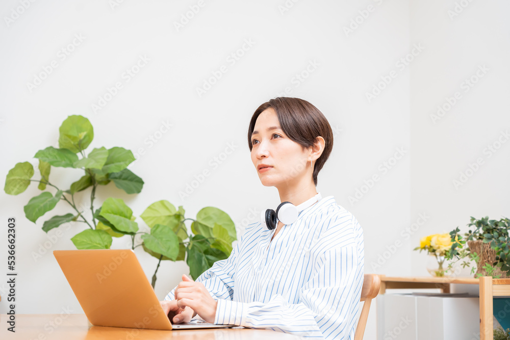 ヘッドホンをつけ考え事をする日本人女性 ヘッドホンをつけ考え事をする日本人女性