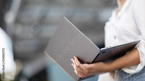 Close-up of a young woman in the city using a laptop computer outside the house. © Witoon