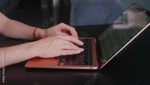 Camera slides around female freelancer's hands typing on laptop keyboard in slow motion. Business woman working at office with internet. Girl working remotely from home. Slow motion tracking shot. photo