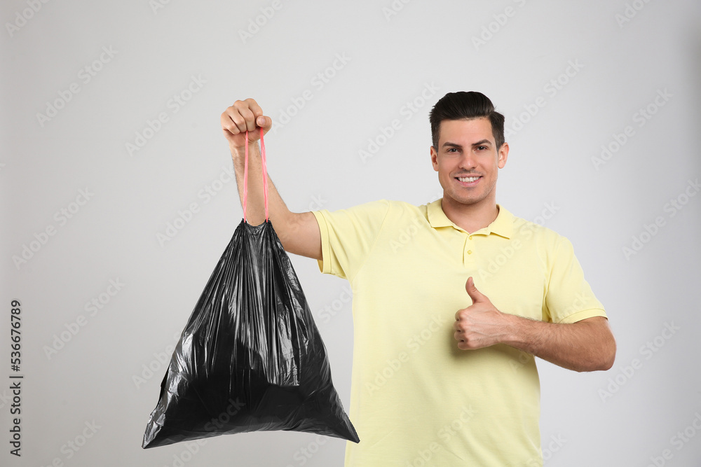 Photography Man holding full garbage bag on light background