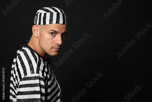 Prisoner in striped uniform on black background, space for text