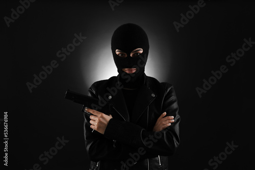 Obraz na plátně Woman wearing knitted balaclava with gun on black background