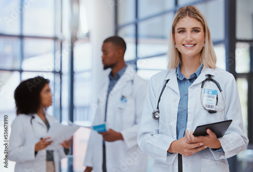 Woman  team and portrait of doctor with tablet in the hospital. Female doctor  smiling and diversity in healthcare  medicine and medical care with doctors smiling  standing and talking
