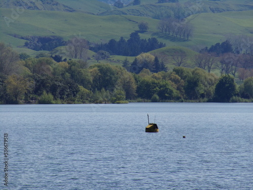 Boat sailing by green hills in New Zealand