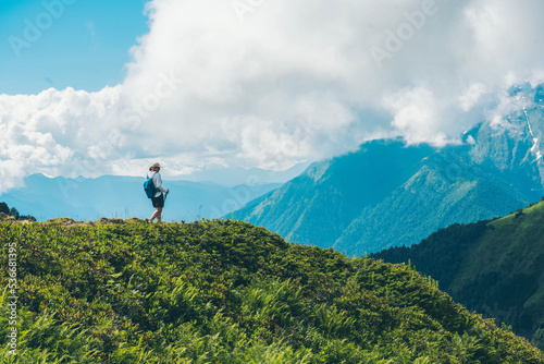 A female traveler with backpack on the top of a mountain. Mountain peaks. Krasnaya Polyana  Sochi  Russia. Climbing the mountain.