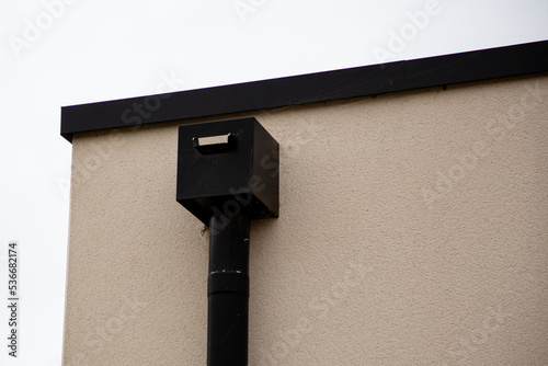 Corner of the house with flat roof with modern gutter pipe