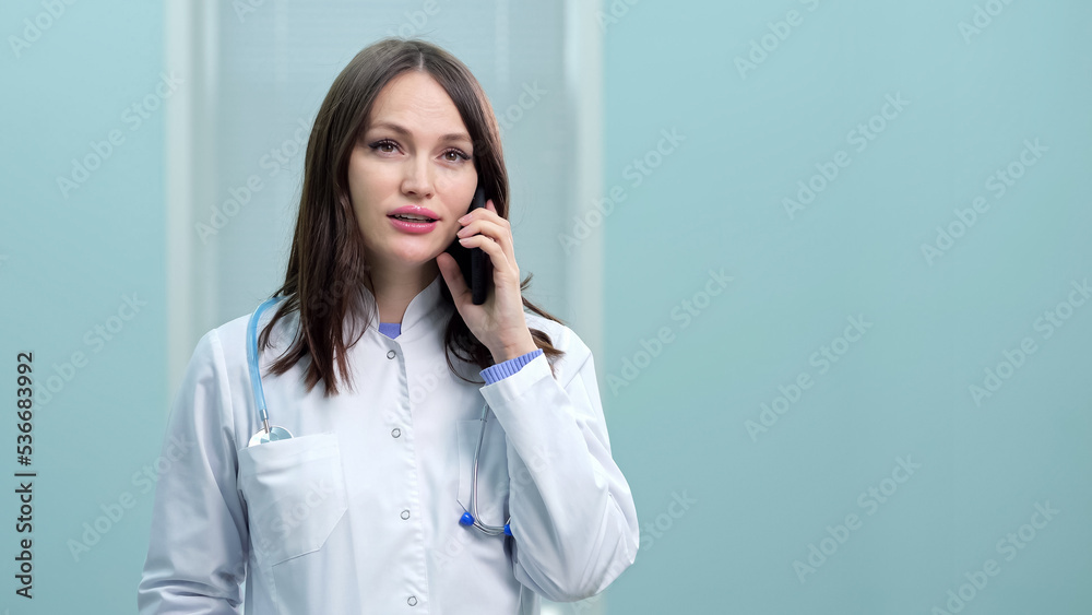 Young woman general practitioner provides telephone consultation at break. Dark-haired doctor advises patient to take new medicines for quicker recovery at flu Young woman general practitioner provides telephone consultation at break. Dark-haired doctor advises patient to take new medicines for quicker recovery at flu