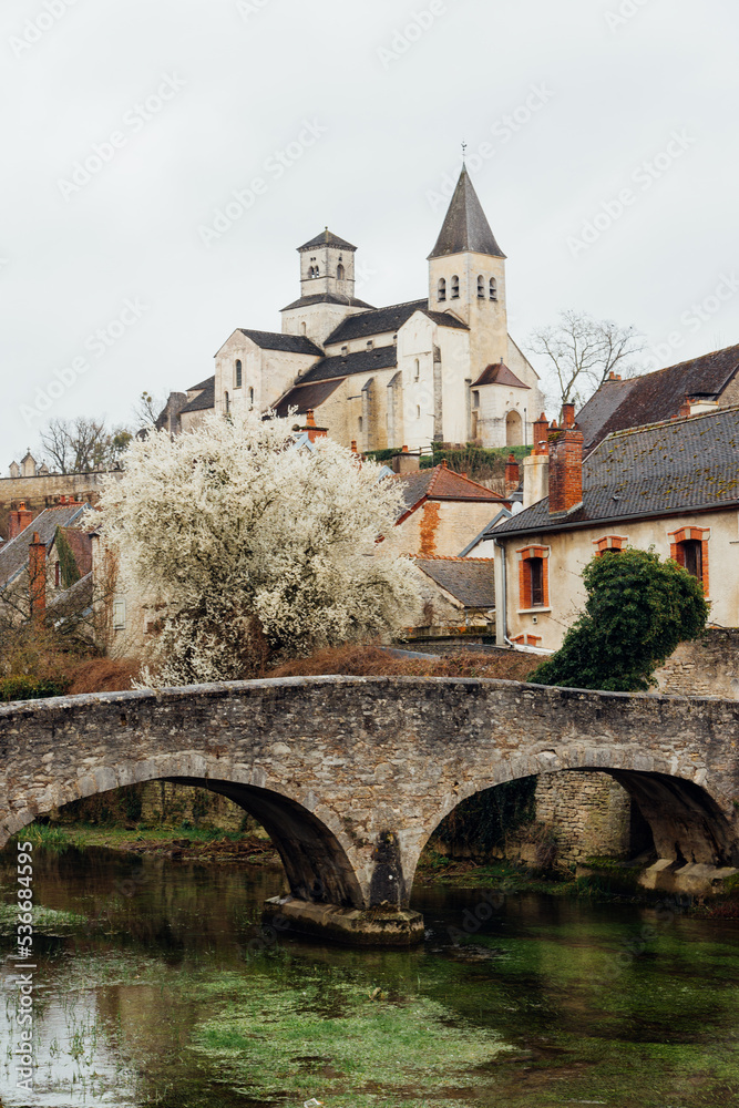 Chatillon-sur-Seine. Un vieux village médiéval. Un pont en pierre sur une rivière. Un arbre en fleur dans une ville ancienne.
