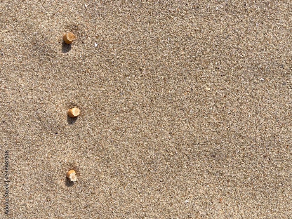 three cigarette butts arranged as bullet points in sand on beach three cigarette butts arranged as bullet points in sand on beach
