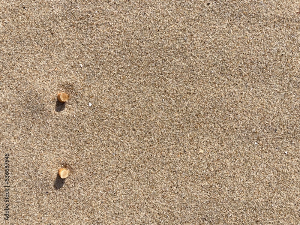 two cigarette butts arranged as bullet points in sand on beach