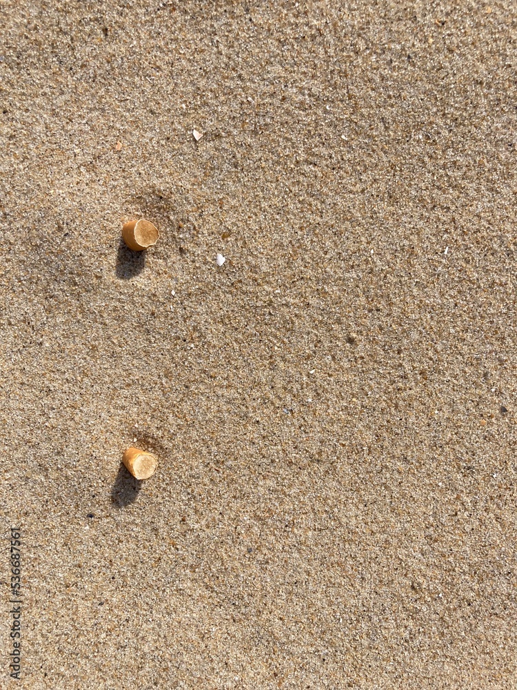 two cigarette butts arranged as bullet points in sand on beach two cigarette butts arranged as bullet points in sand on beach