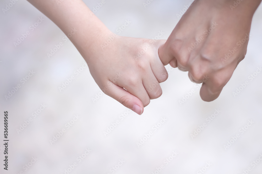 Asian child girl hand holding mother hand making a pinkie promise on background Asian child girl hand holding mother hand making a pinkie promise on background