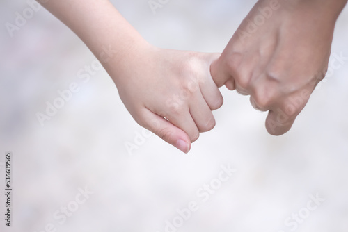 Asian child girl hand holding mother hand making a pinkie promise on background