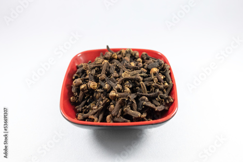 Pile of organic fresh whole clove buds in a bowl isolated on white background. close up.top view.