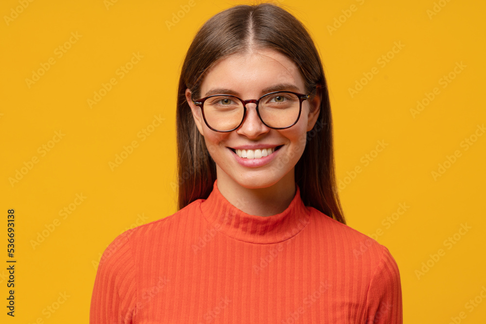 Headshot of smiling intelligent businesswoman feeling confident on yellow background