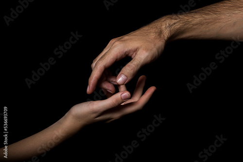Gentle touch of female and male hands on a black background. Gesture expressing love and tenderness
