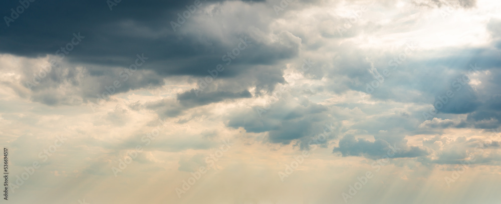 Dramatic Sky Background with sunny beams. Panoramic view of Stormy Clouds in Dark sky